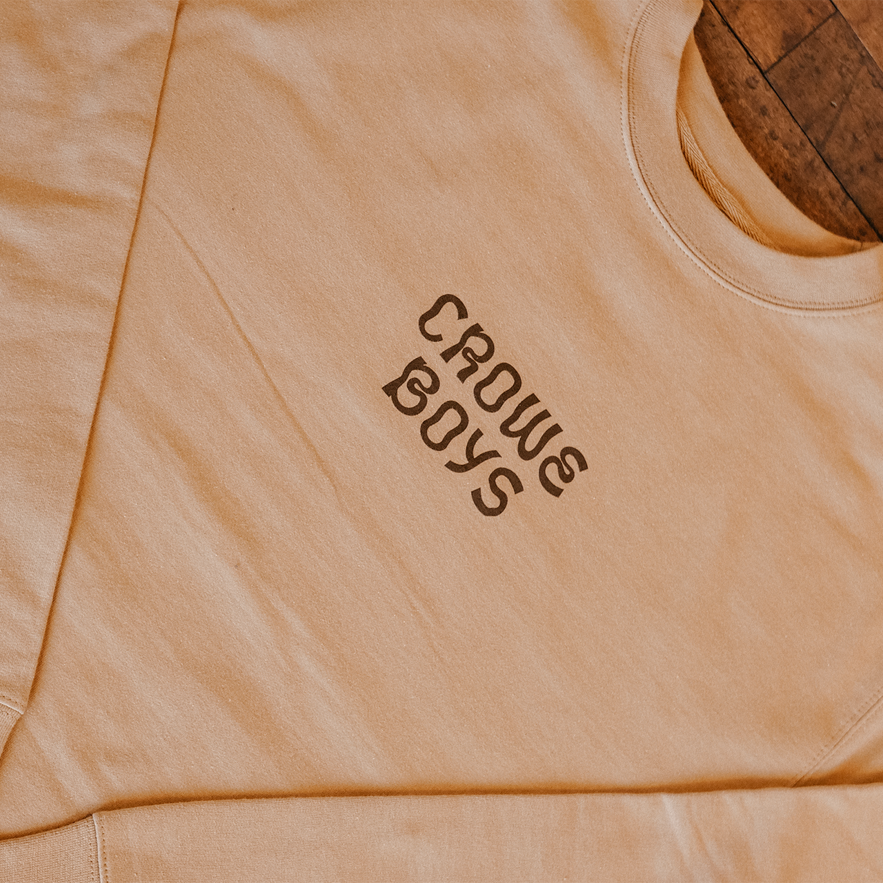 crowe boys tan mushroom crewneck laying on wooden floor